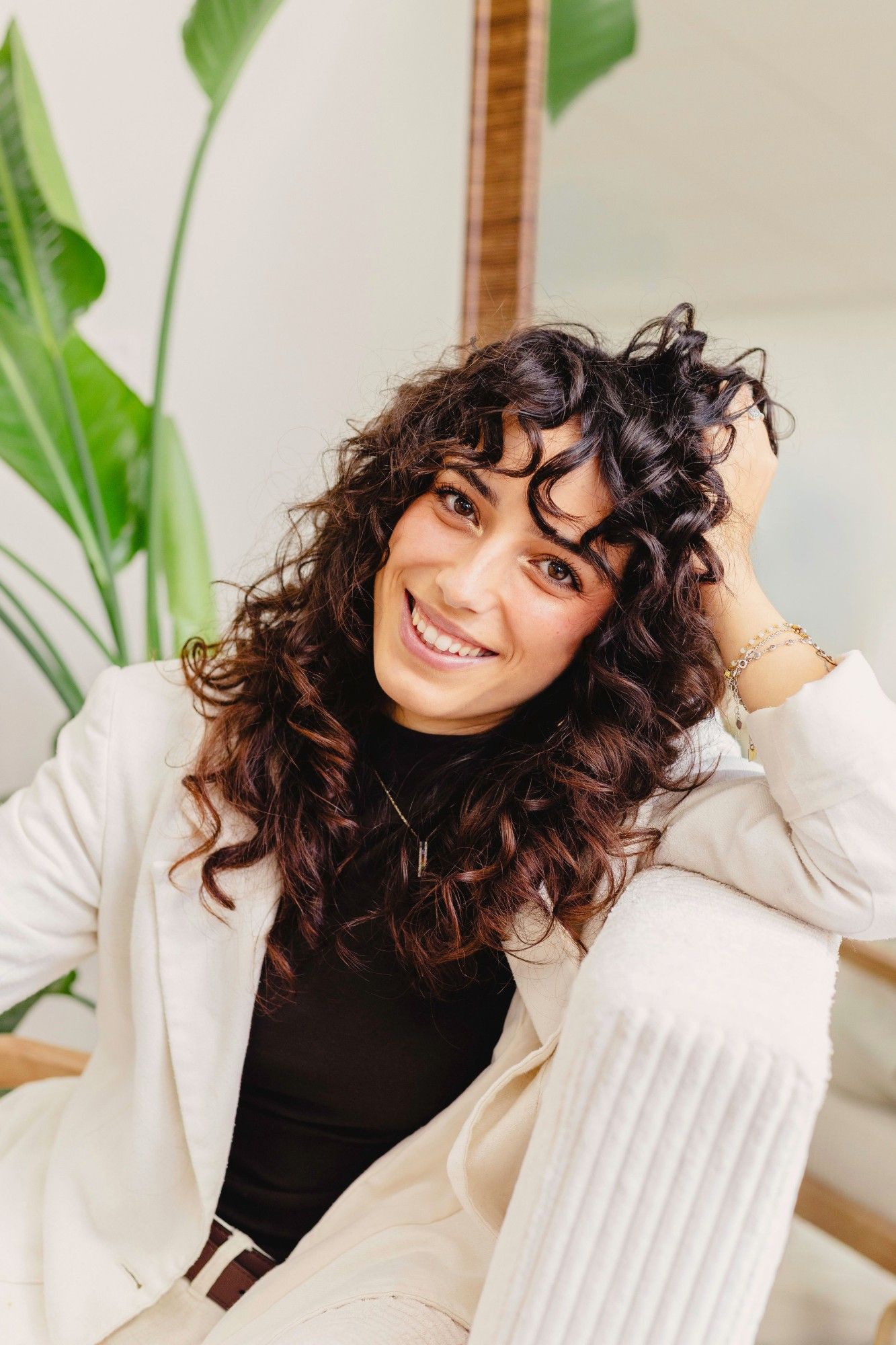 Portrait de Jessica Afonso, souriante, la main dans ses cheveux bouclés
